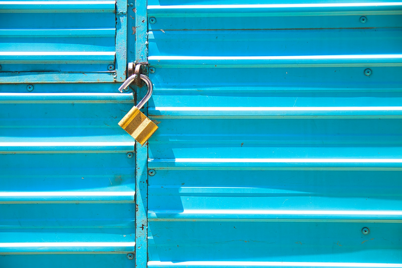 Gembok kuning pada pintu besi biru yang sulit dibuka